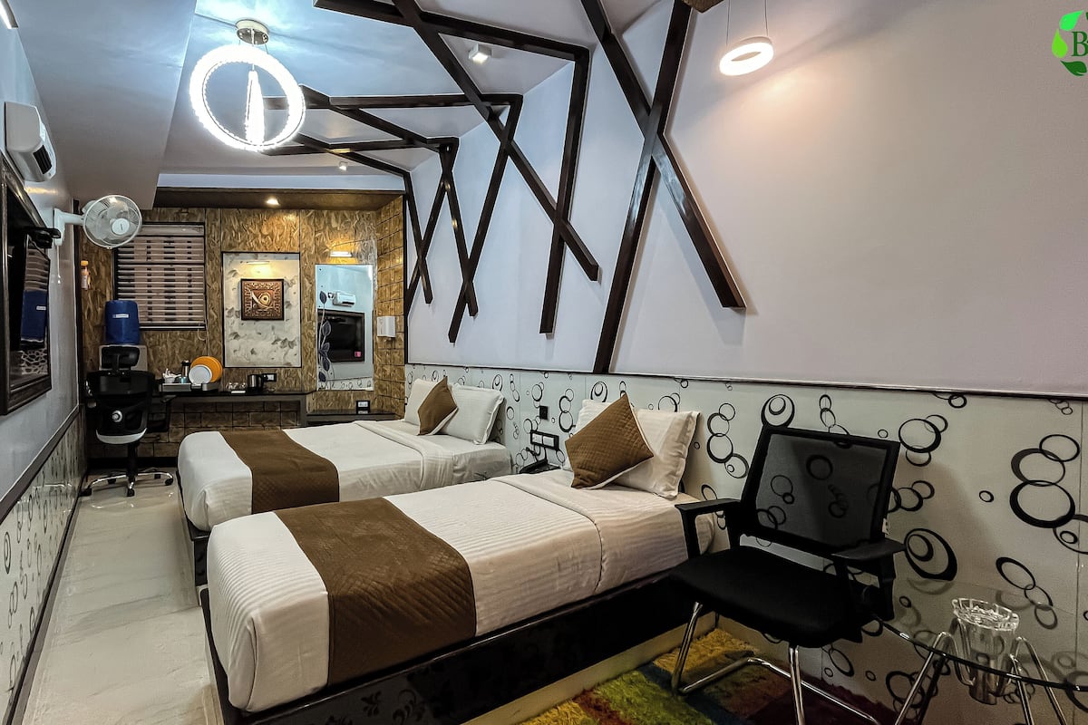 A modern hotel room with two beds, a desk, and a chair.