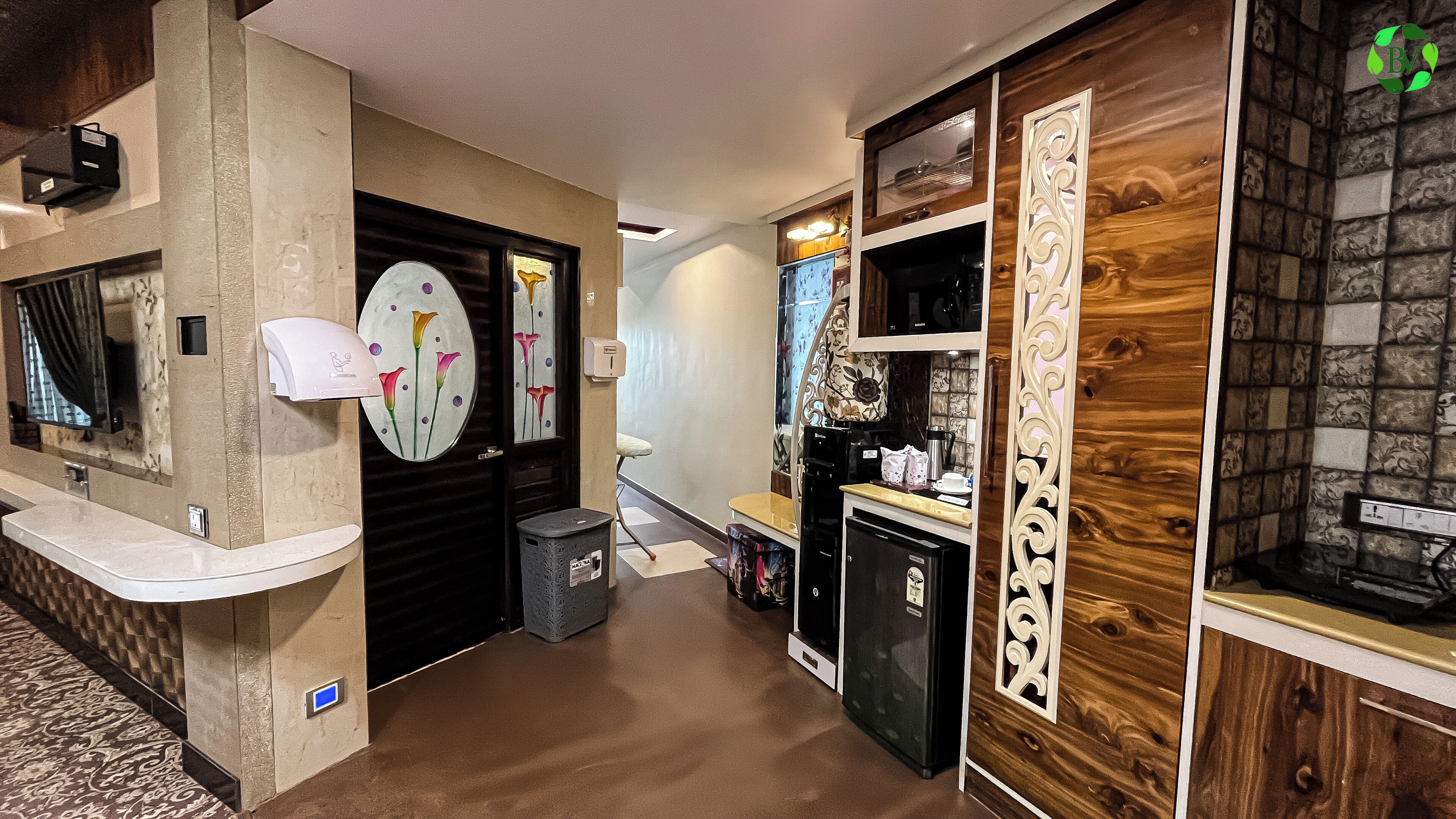 A hallway with a reception desk, a trash bin, a refrigerator, and a microwave.