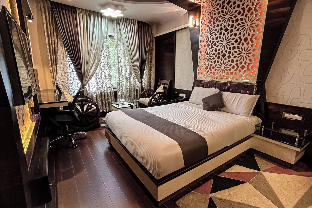 A modern hotel room with a large bed, a desk, and a chair.