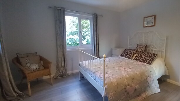 Une chambre à coucher avec un lit, une chaise, une fenêtre et une porte.