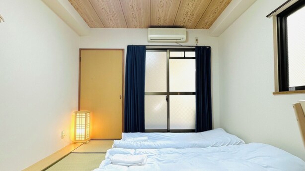 A room with a bed, tatami mat flooring, a sliding door, and a window with curtains. - Along the airport line, 2 min. from Hanazono station, Japanese-style room with private bathroom Apartment for rent [ 202]. (大阪市)