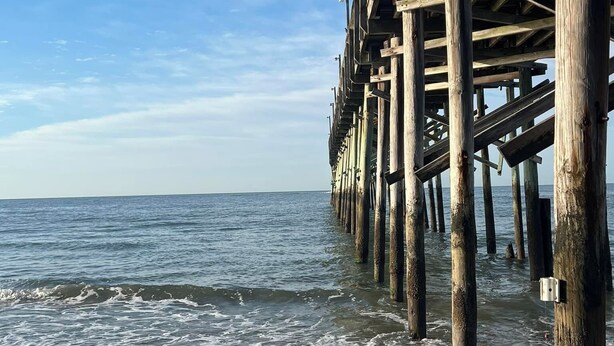 Un muelle de madera que se adentra en el mar bajo un cielo despejado.