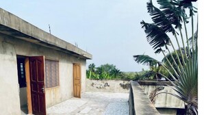 Um pátio com piso de azulejos, parede de concreto e um edifício com porta de madeira.