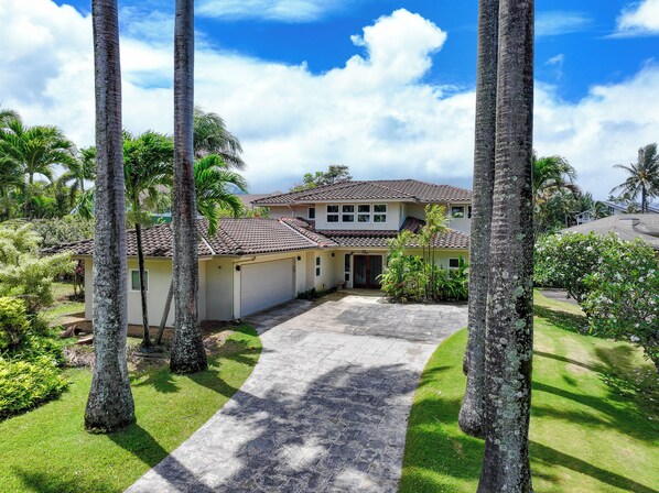 A two-story house with a tiled roof, surrounded by palm trees and a well-maintained lawn. - Privacy and Elegance in Princeville (Princeville)