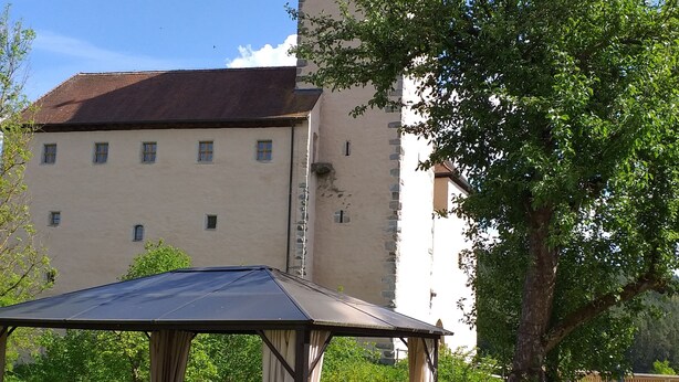 A castle with a tower, a covered patio with furniture, and a lawn. - Sylvia's castle view (Trausnitz)