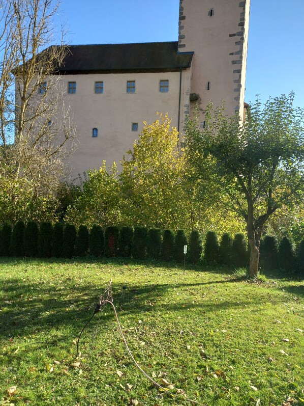 A building with a tower, surrounded by a well-maintained lawn and trees.
