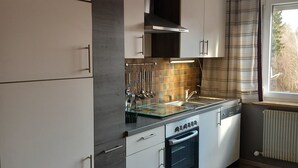 A modern kitchen with white cabinets, a stainless steel range hood, and a built-in oven. - Sylvia's castle view (Trausnitz)