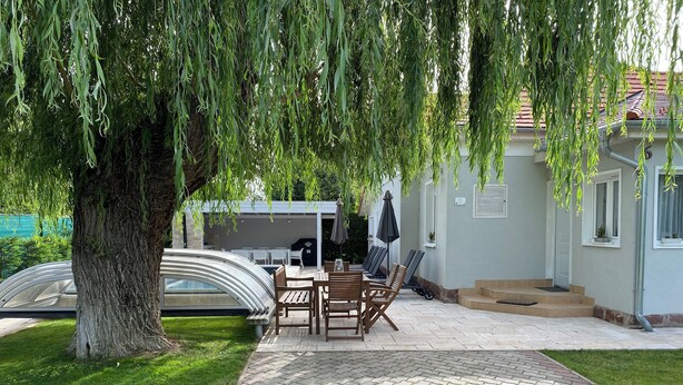 Un patio con mesa y sillas, una zona de estar cubierta y una piscina.