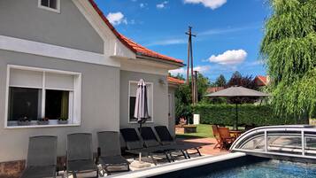 Relax by the serene pool surrounded by lush greenery and a picturesque bridge.