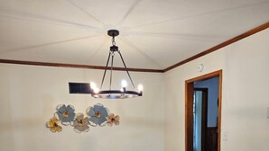 Ein Esszimmer mit Holztisch, weißen Stühlen, einem gemusterten Teppich und einer Deckenleuchte.