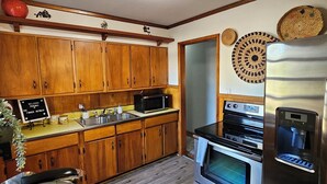Eine Küche mit Holzausstattung, einer Mikrowelle, einem Backofen, einem Kühlschrank und einer Kaffeemaschine.