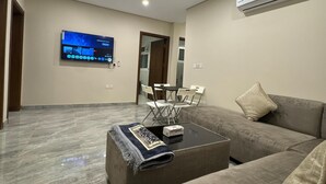 Un salon moderne avec un canapé, une table basse et un téléviseur à écran plat fixé au mur.