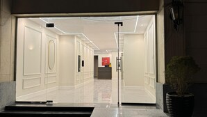 L’entrée d’un hôtel moderne, avec une porte en verre, un comptoir d’accueil et une plante en pot.