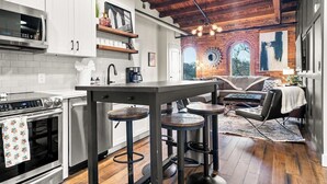 A modern kitchen with white cabinets, a stainless steel oven, and a bar area with stools.