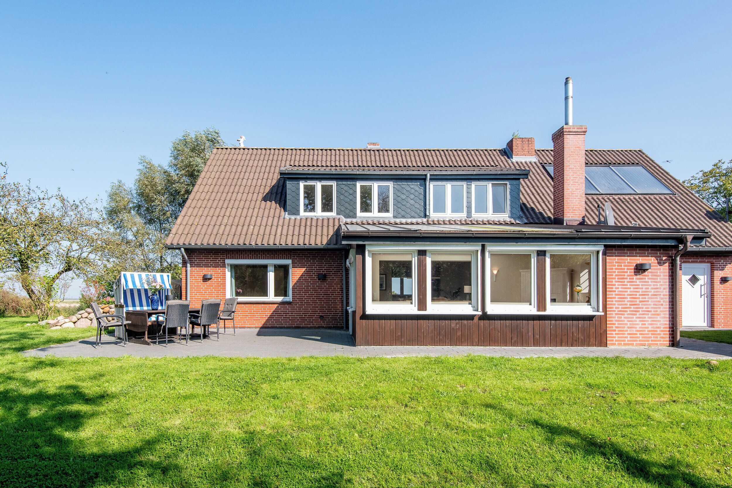 Et tosiders hus med facade i mursten, store vinduer og skorsten.