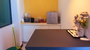Una cocina compacta con una pared de acento amarilla, un refrigerador y una mesa de comedor con sillas.