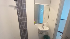 Un baño pequeño con ducha, lavabo y espejo.