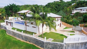 A modern resort with a swimming pool, palm trees, and a stone wall. - Oceanview Luxury Villa, 6 bedrooms, WiFi, AC, breakfast Preparation included (Las Terrenas)
