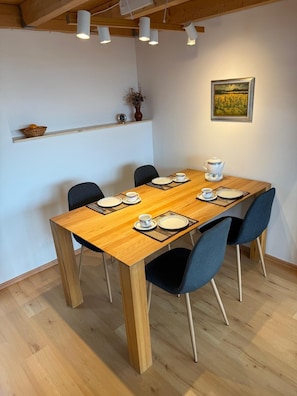 A dining area with a wooden table, black chairs, white plates, and a teapot. - Lakehouse - Peaceful Arpartment Overlooking the Lake (Angermünde)