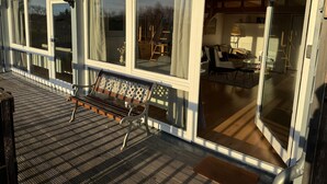 A modern house with large windows, a wooden deck, and a cozy interior with furniture.