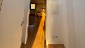 A narrow hallway with a skylight leading to a bedroom.