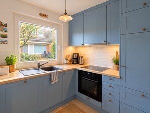 A modern kitchen with a window, built-in cabinets, a sink, and an oven.
