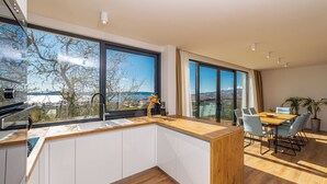 Une cuisine moderne avec un plan de travail en bois, des armoires blanches et une grande fenêtre offrant une vue panoramique.