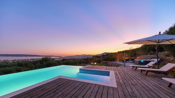 Une terrasse en bois avec une piscine, des chaises longues et un parasol.