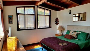 Une chambre à coucher avec un lit, une table de chevet, une lampe, un miroir et une fenêtre.