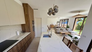 Eine moderne Küche mit Marmorarbeitsplatte, Holzschränken und einem Essbereich mit großem Tisch und Stühlen.