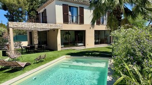 Ein modernes Haus mit Swimmingpool, Sitzgelegenheit im Freien und einer Steinmauer.