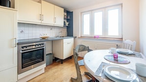 A kitchen with white cabinets, a stove, and a dining table set for two.
