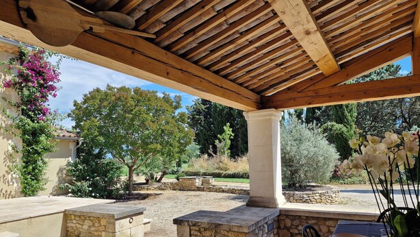 Eine Terrasse im Freien mit Steinböden, Holzbalken und einer Steinsäule.