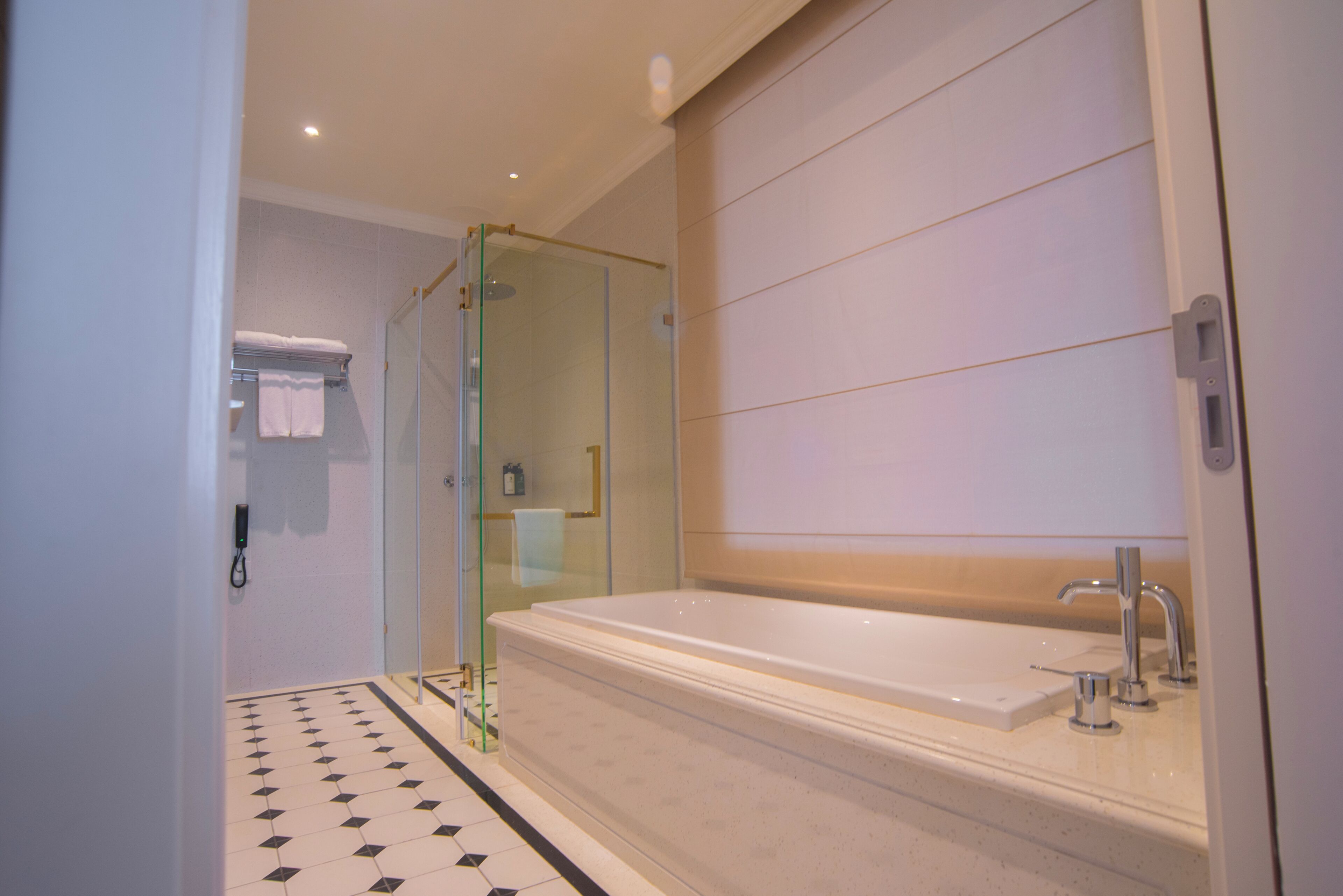 A modern bathroom with a glass-enclosed shower, a large bathtub, and a tiled floor.
