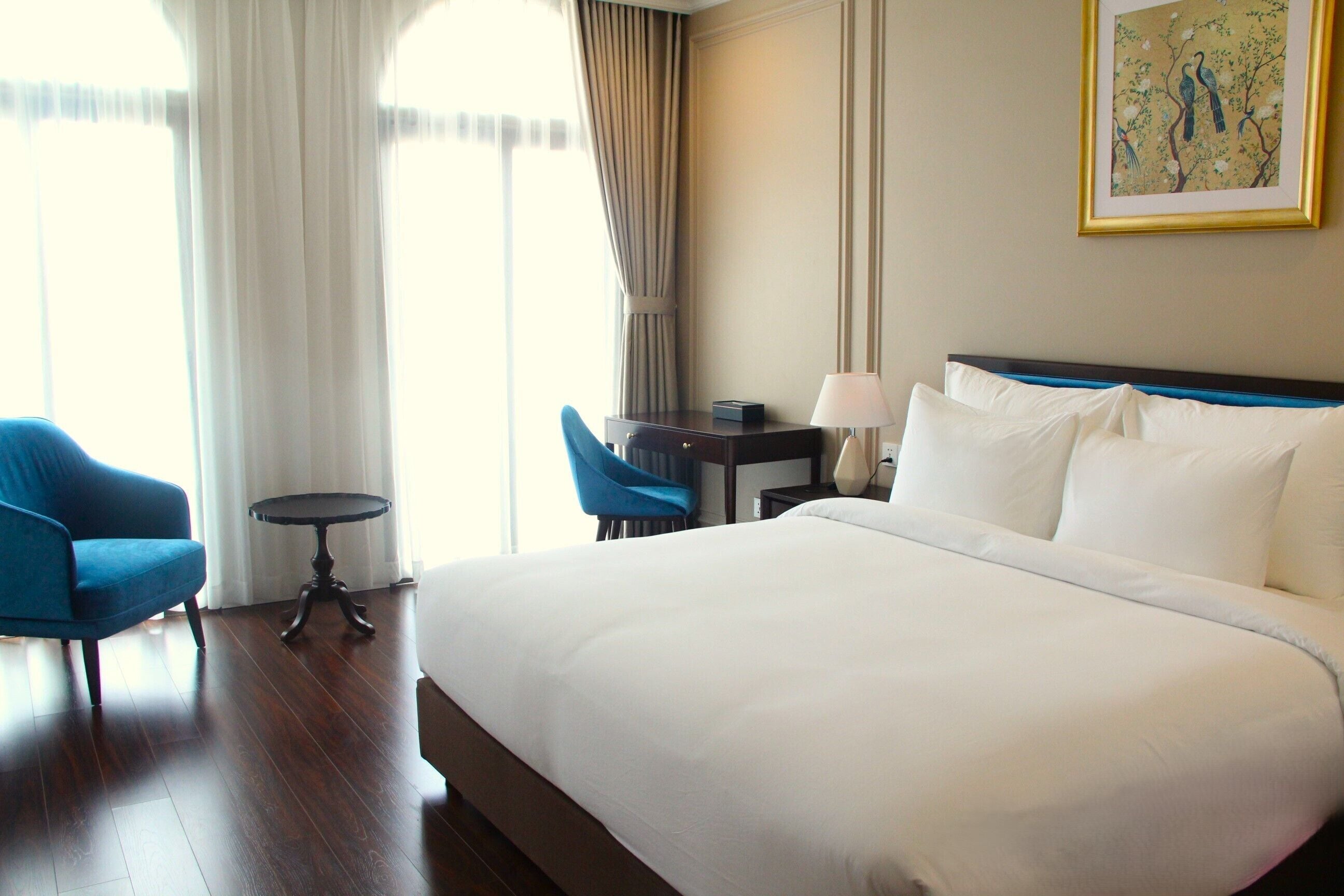 Una habitación de hotel con una cama grande, un escritorio, una silla y una lámpara.