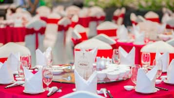 A banquet table set with white napkins, plates, and wine glasses, with a menu sign in the center.
