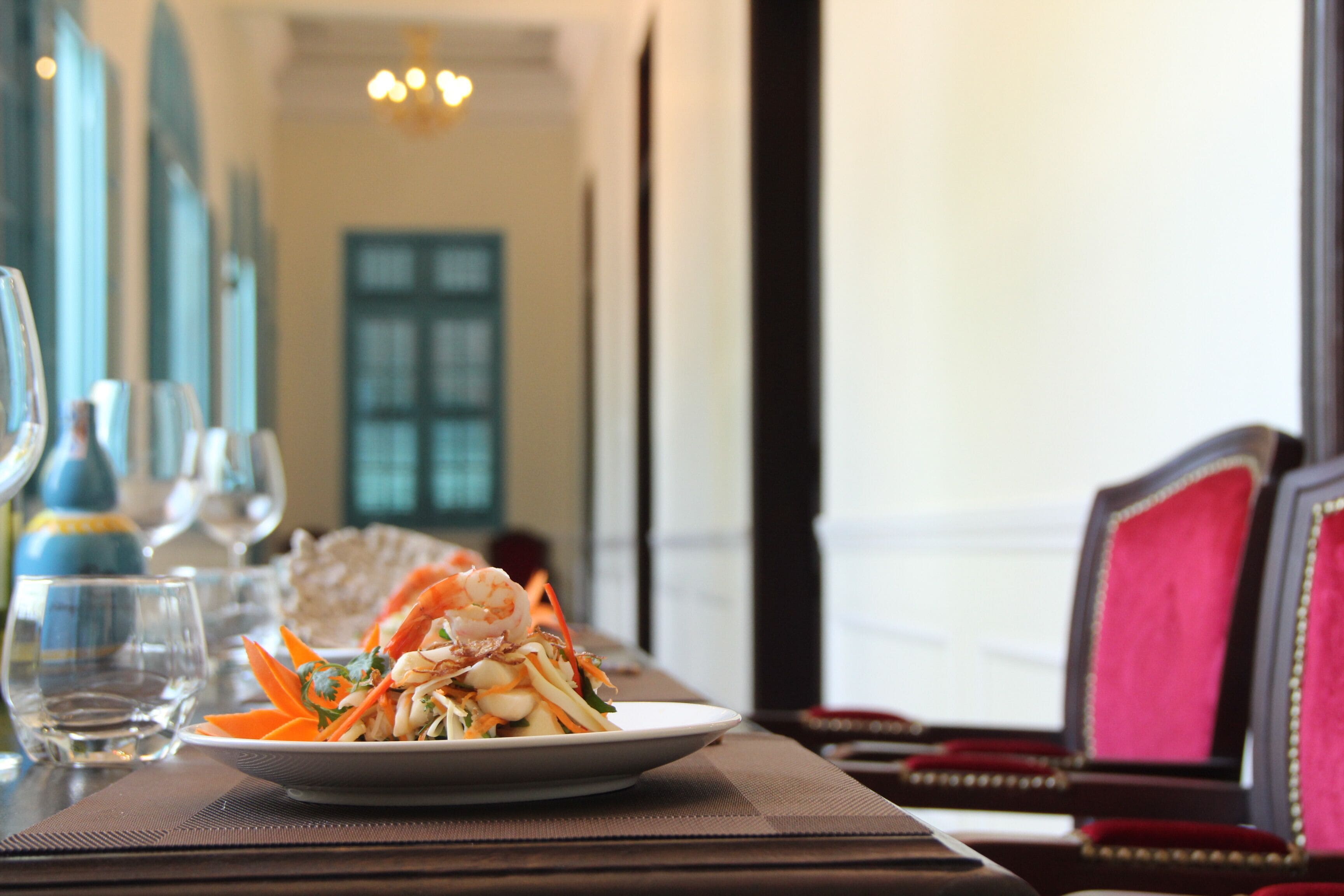 A dining table with a plate of food, glasses, and a chair.