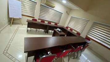 A conference room with a long table and red chairs, whiteboard, and air conditioning units.