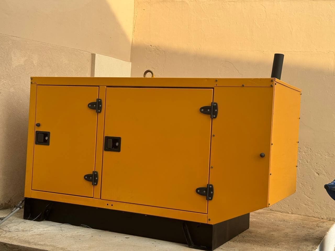 A yellow metal cabinet with two doors and a handle, placed against a wall.