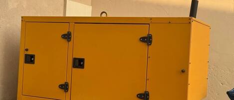 A yellow metal cabinet with two doors and a handle, placed against a wall.