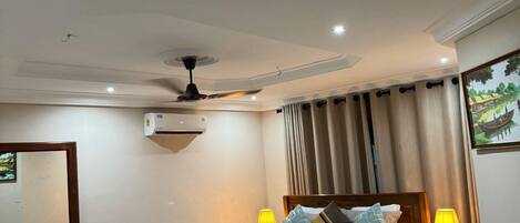 Una habitación de hotel moderna con una cama grande, un escritorio, una silla y un ventilador de techo.
