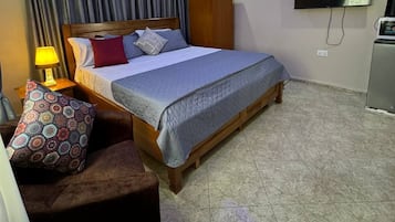 A hotel room with a bed, a TV, an air conditioner, and a ceiling fan.