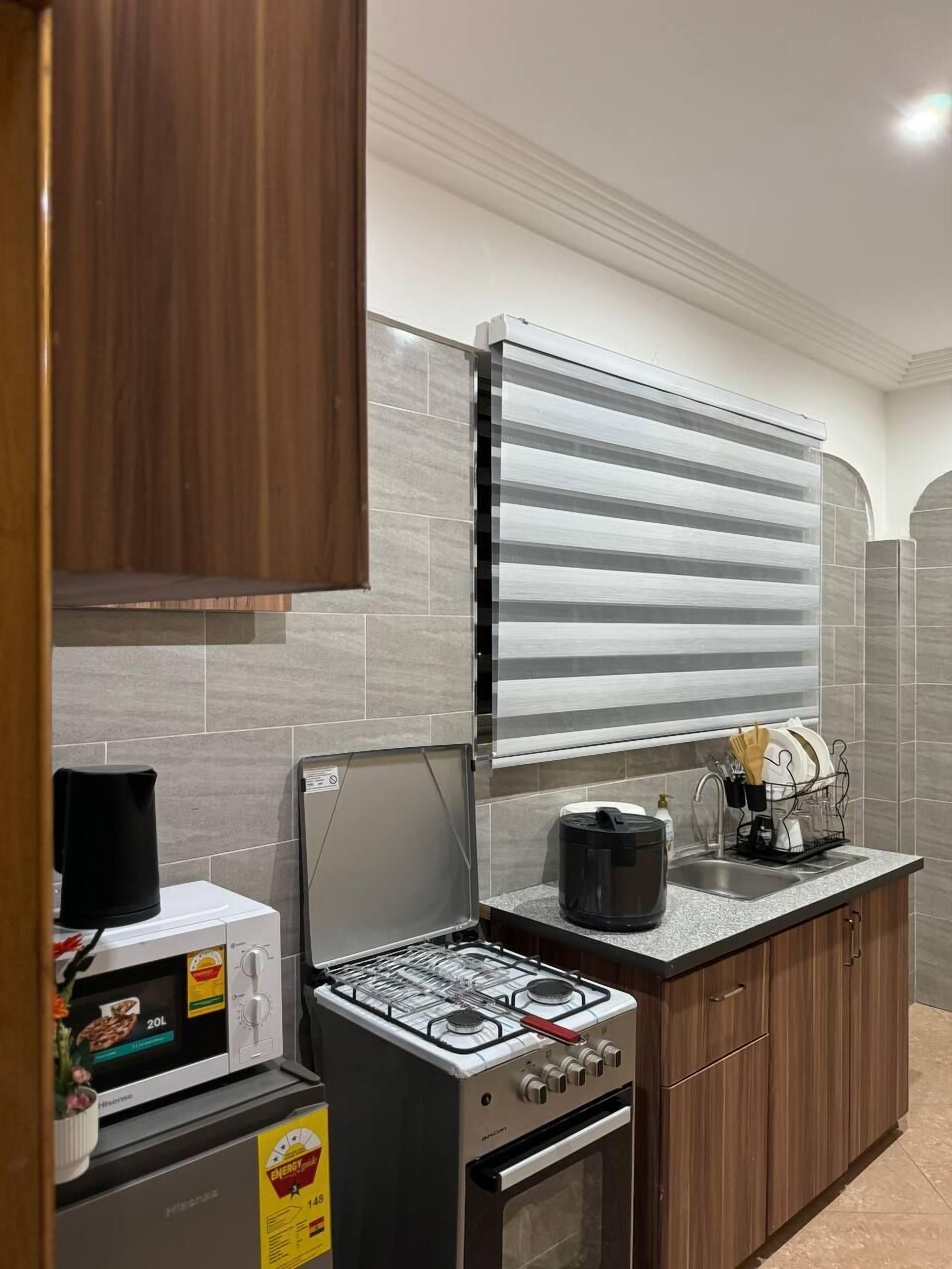 A kitchen with a stove, oven, microwave, and a dish rack with utensils.