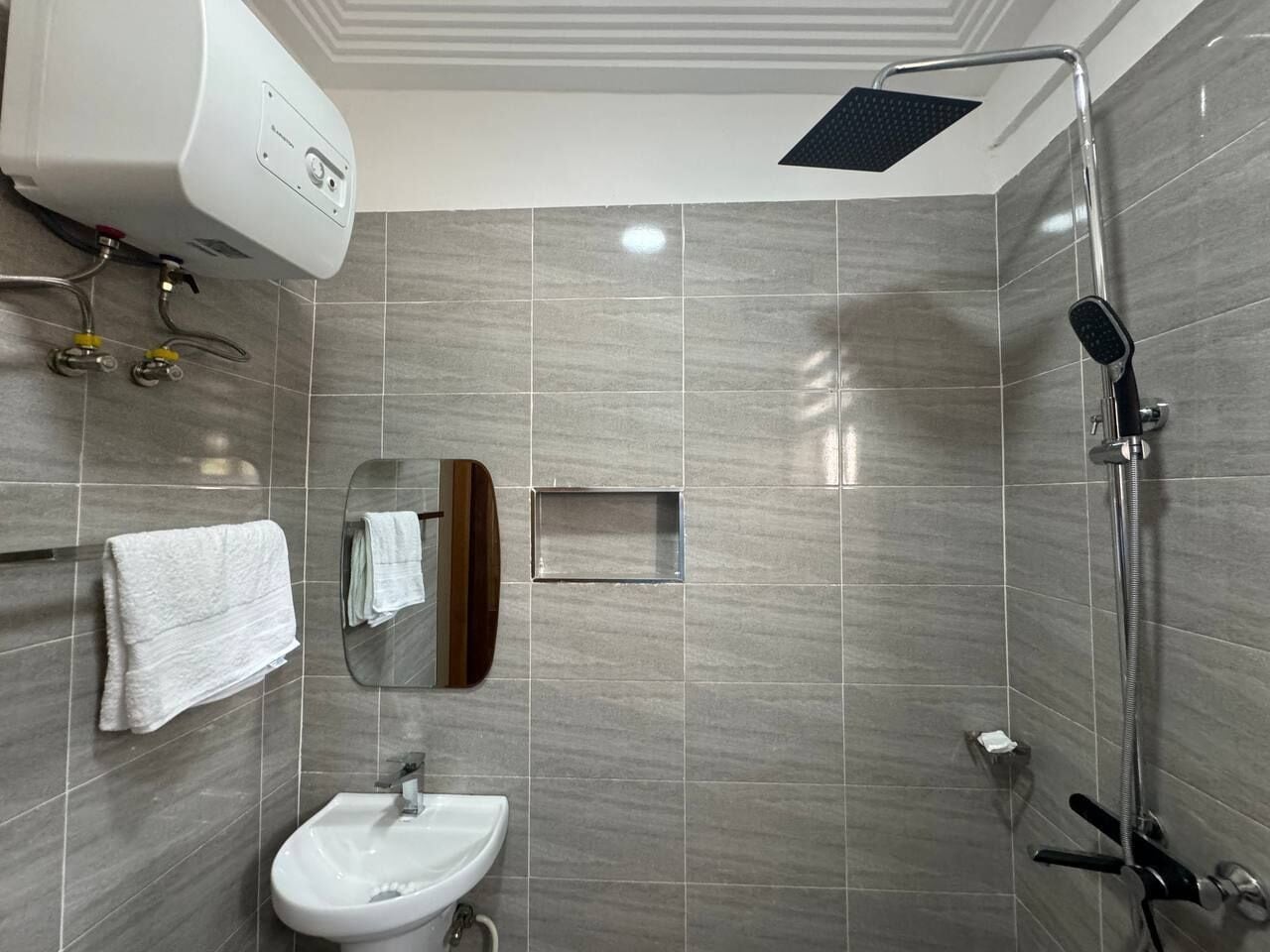 Een moderne badkamer met een douche, een wastafel en een handdoekhouder.