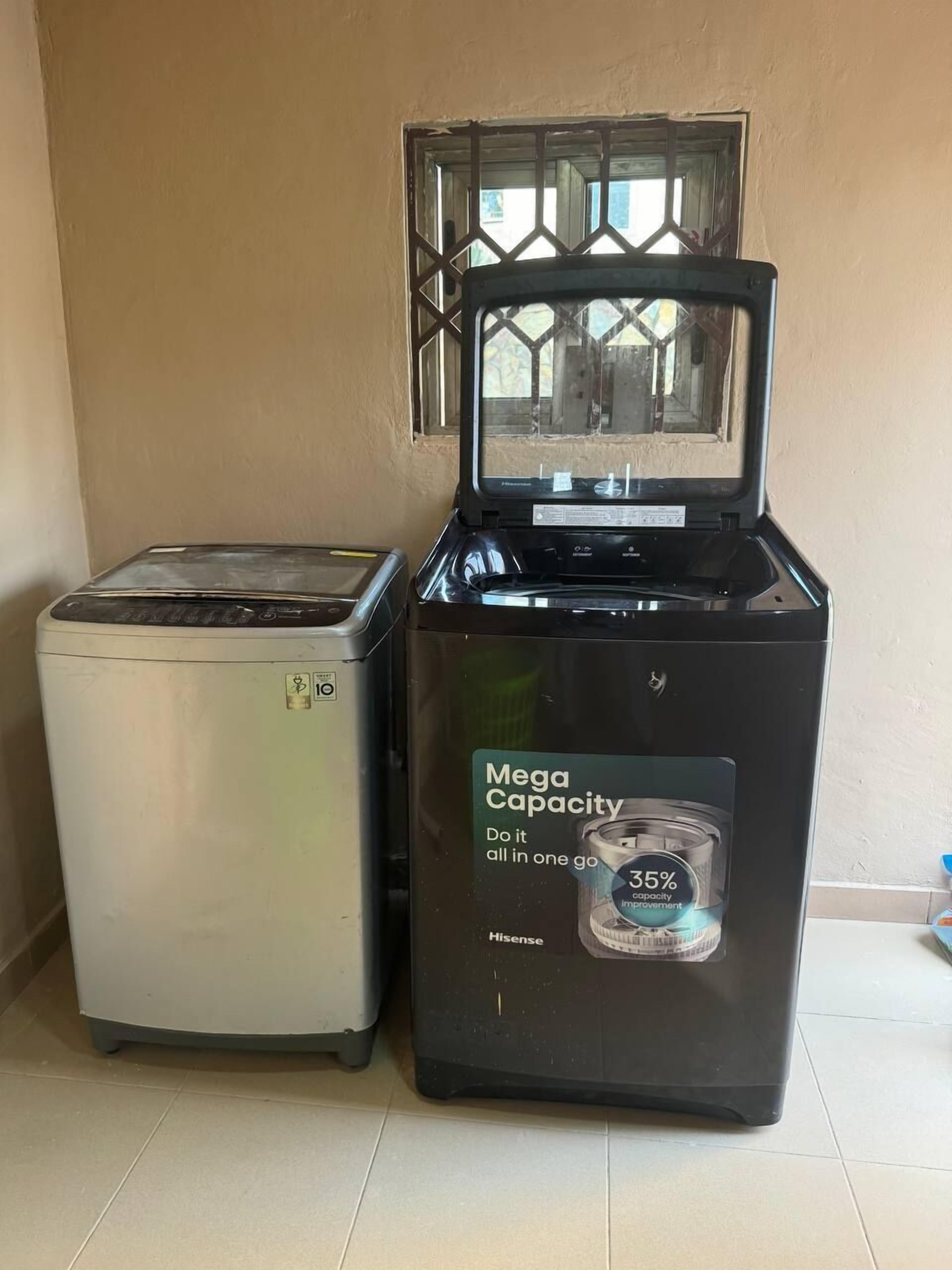A compact kitchen setup with a white refrigerator and a black Hisense microwave with a water dispenser.