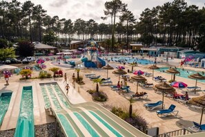 Een waterpark met diverse zwembaden, een waterglijbaan en ontspanningsgebieden met parasols.