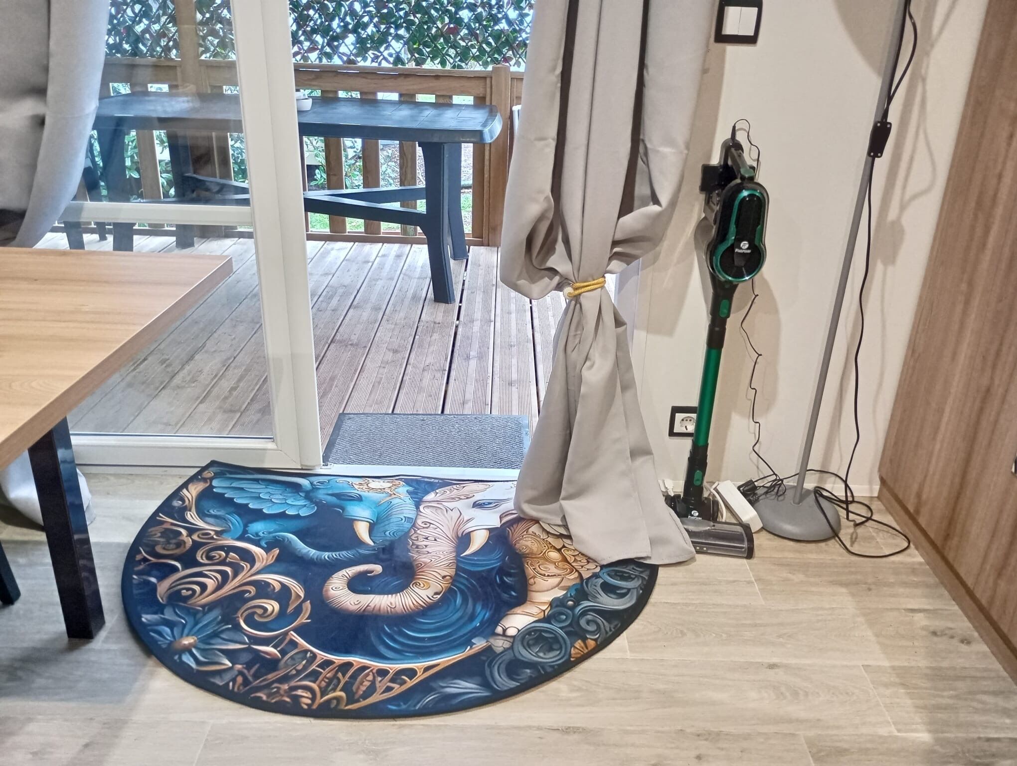A room with a wooden floor, a round rug with a dragon design, a table, and a chair.