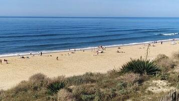 A beach with people, clear skies, and calm water.
