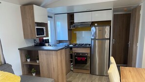 Eine kompakte Küche mit Mikrowelle, Herd, Backofen und Kühlschrank. Es gibt eine kleine Sitzecke mit einer Couch und einem Tisch.