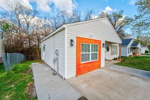 A single-story house with a garage door, a small porch, and a visible number "1201" on the side.
